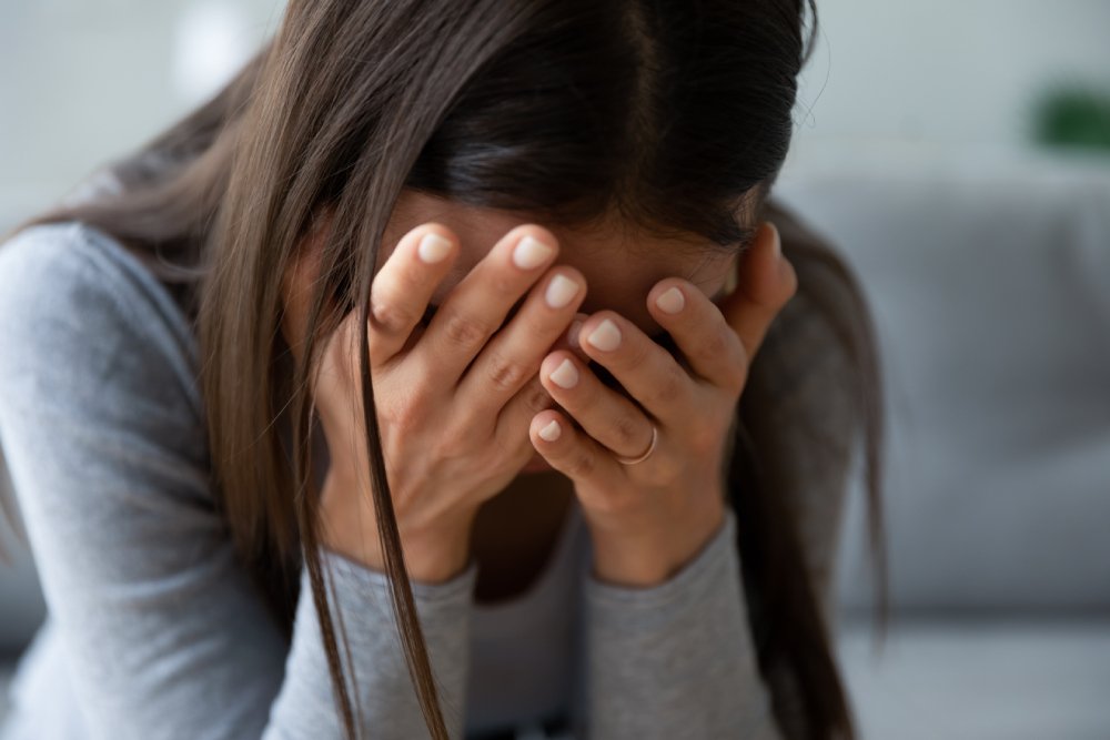 Cerrar infeliz, llorando, culpable, triste joven escondiendo la cara en las manos